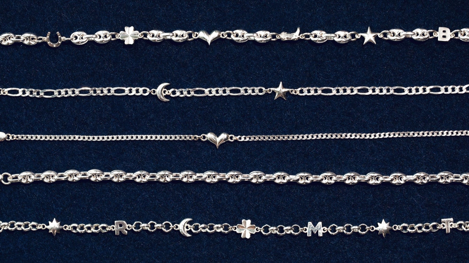Collection of silver chains with various designs on a dark blue background
